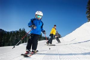 Familie mit Ski und Snowboard auf der Piste.