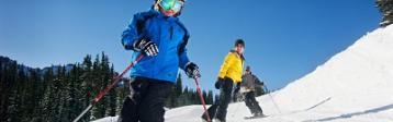 Familie mit Ski und Snowboard auf der Piste.